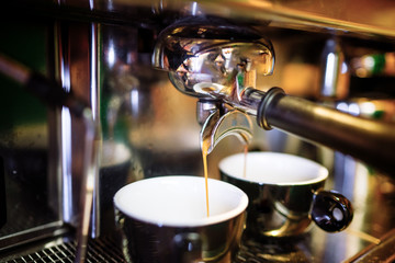 Two espresso pouring from espresso coffee machine. Hot beverages, coffee preparation and barista details