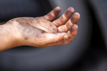 Closeup of young man dirty hands and tyre outdoors