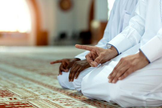 Muslim men praying with holy books in mosque