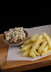 French fries and salad with mayonnaise on the board