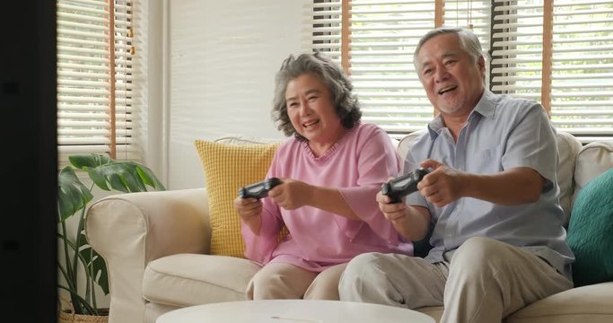 Asian senior couple playing game together at home with happy emotion. People with relaxation, old age, retirement, senior lifestyle family concept.