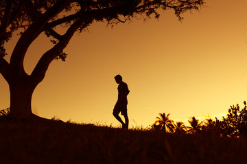 Silhouette of young man walking outdoors. 