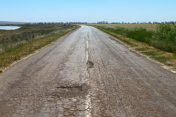Old a little damaged asphalt road in steppe or field, industrial photo