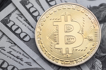 Gold Bitcoin on hundred dollars bills.