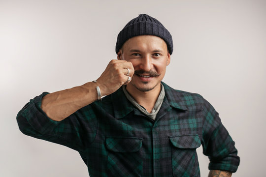 Portrait of kind cheerful smart professional friendly expert handsome handyman wearing knitted hat standing isolated on gray background copyspace
