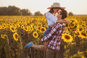 loving couple is walking in a blooming sunflower field
