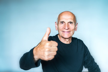 Happy positive elderly man in black T-shirt, thumb up, selective focus.