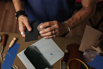 Moments of modelling design of custom made pocketbook. Workplace of Leather designer. Hands of...