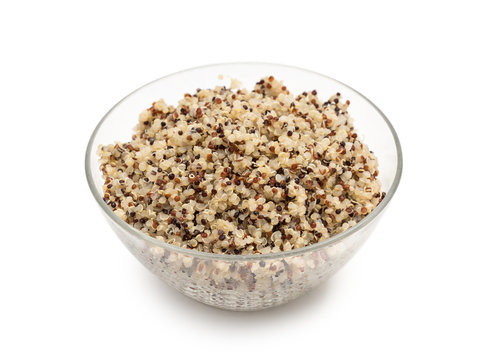 Cooked mixed quinoa seeds in a round glass bowl seen obliquely from above and isolated on white background