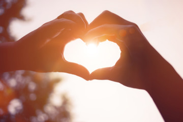Fototapeta premium ręce w kształcie serca, niebo przechodzi promień słońca
