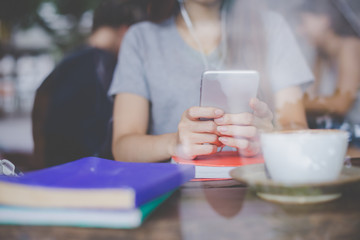 Close up honding yong woman sitting at a cafe using smart phones to receive text messages. Mockup image.