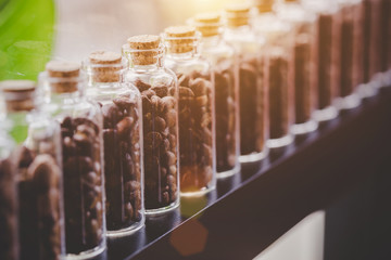 Close up coffee beans in glass bottles lined up in rows, Warm light.