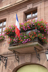 Naklejka premium Drapeau français sur un balcon fleuri
