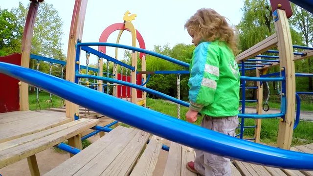 The child moves neatly over the bridge on the playground. Slow motion.