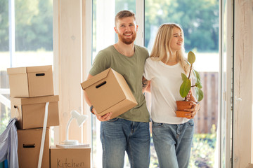 Moving to new home. Happy couple holding cardboard boxes while going into the house