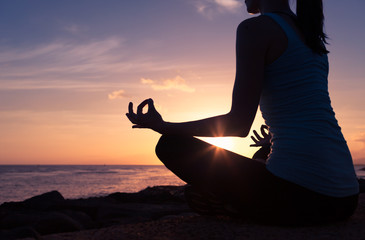 Peaceful relaxing meditation. Female meditating against beautiful sunset. 