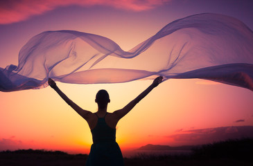 Woman holding silk cloth blowing in the wind. Freedom concept. 
