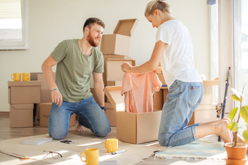 Young couple unpacking cardboard boxes at new home. Moving house