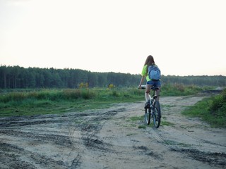 Polonne / Ukraine - 14 September 2018: girl in a green T-shirt with a backpack riding a bike