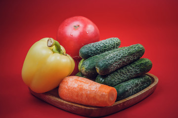 fresh vegetable set on a bamboo plate. on red background. isolate