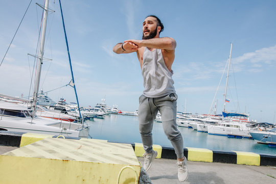 Sportsman fit male jumper doing explosive strength training jumps, crossfit fitness workout strenght power concept . Handsome strong man exercising on sky and sea background. - Powered by Adobe