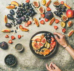 Healthy seasonal fall breakfast variety. Flat-lay of Greek yogurt, fresh fruit, chia seeds bowl and female hands over grey concrete background, top view. Clean eating, vegetarian, dieting food
