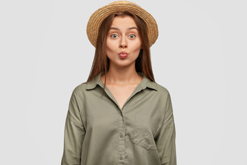 Beautiful youngster with pleasant appearance, keeps lips round, going to kiss someone, wears...