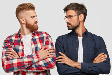 Photo of serious male opponents stand crossed hands, look at each other, have competiton, stand...