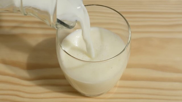 Vertiendo leche en un vaso en la mesa