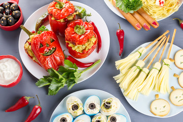 Halloween party food. Red stuffed peppers with scary cutout faces, witches brooms of cheese and other treats