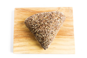 Triangle-shaped wholemeal bread with flax seeds, oats and sesame on a wooden board
