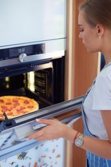 Fototapeta na wymiar Happy young woman cooking pizza at home