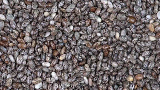 Pile chia seeds  background, close up rotation loopable 4k top view. Food  background. Gastronomy concept, organic food. Macro chia seeds