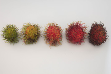 Different color rambutan fruits on white background