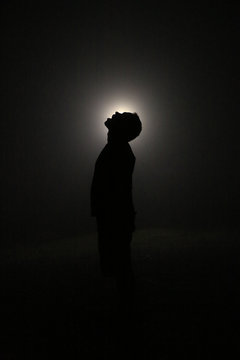 Silhouette in the Dark, Head Leaning Backwards with Open Mouth. Light behind Head.