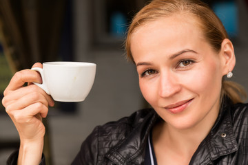 Young beautiful woman with a cup of coffee in a outdoor cafe, girl have a lunch on terrace
