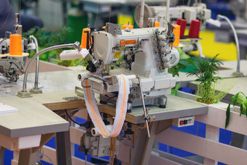 Professional overlock sewing machine in workshop. Equipment for edging, hemming or seaming clothes at tailors shop.