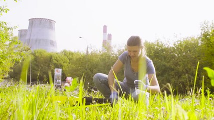 Woman ecologist getting samples of soil near the thermal power plant. Crane shot. Damage appreciate to nature in an urban environment