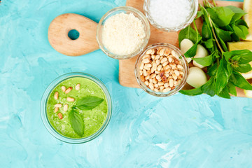 Homemade pesto sauce in glass jar with ingredients.