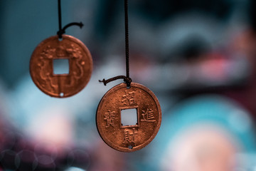 Oriental, magical pendants. Traditional asiatic and chinese currency, transformed into fortune coins with powerful engravings. Bronze, copper, gold necklace, black thread, blurry background. 