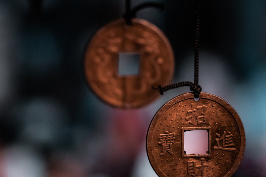 Oriental, magical pendants. Traditional asiatic and chinese currency, transformed into fortune coins with powerful engravings. Bronze, copper, gold necklace, black thread, blurry background. 