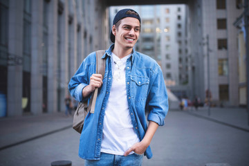 Cheerful young man with backpack enjoying walk the city