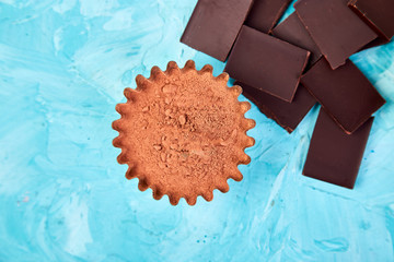 Cocoa beans background on blue table. Dark chocolate pieces