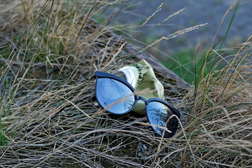 Sunglasses and an old can in the grass - environment garbage