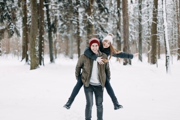 Fototapeta na wymiar happy young people, couple in winter snowy forest. beautiful lovers having fun.
