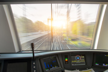 Naklejka premium Kabina maszynisty szybkiego pociągu pasażerskiego, widok na tor z efektem rozmycia prędkości.