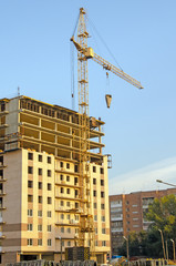 Fototapeta premium Construction of a multi-storey building. Crane at work. Workers on the top floor. Brick. Russia