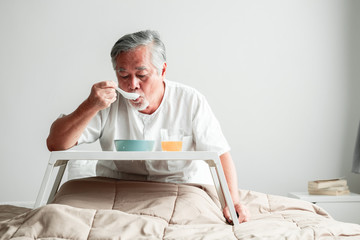 Senior man in bed enjoying breakfast.