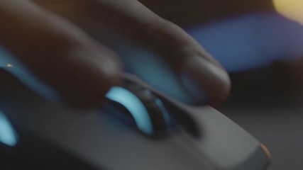 Video gamer or hacker. Hand on computer mouse with RGB backlight. Close-up dolly panning. Shallow depth of field