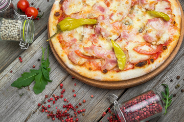 Pizza with tomatoes, mozzarella cheese, black olives and basil. Delicious italian pizza on wooden pizza board.